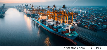 Cargo ship docking at busy harbor with cranes unloading 130619335