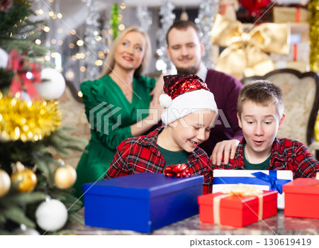 Smiling family celebrating Christmas and giving each other gifts Smiling family celebrating Christmas and giving each other gifts 130619419