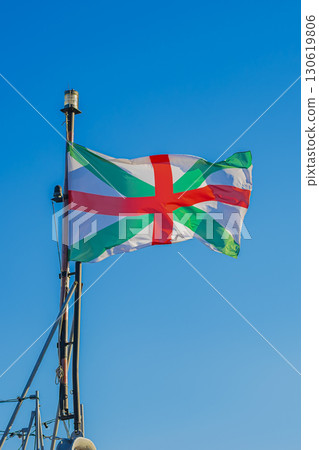 Colorful naval flag with red and green cross waving on ship mast against clear blue sky, Bulgarian Navy. Concept of maritime identity, naval tradition, national seafaring heritage Colorful naval flag with red and green cross waving on ship mast against clear blue sky, Bulgarian Navy. Concept of maritime identity, naval tradition, national seafaring heritage 130619806