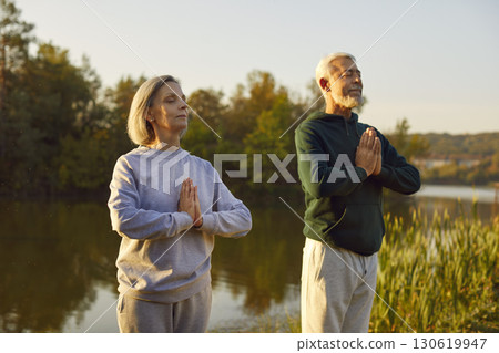 Active senior couple doing yoga exercises in nature. Outdoors fitness concept. 130619947