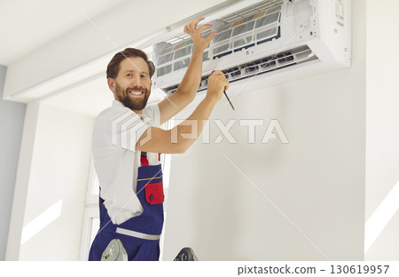 Happy air conditioner maintenance service worker changing filters or repairing some details 130619957