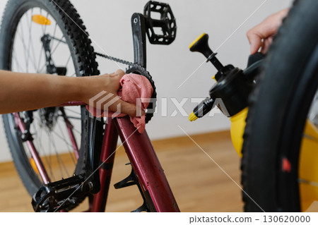 Close-up of two mechanics male cleaning mountain bike using spray bottle and cloth, wiping down frame and ensuring proper maintenance after trail riding, preserving cycling gear condition and service. Close-up of two mechanics male cleaning mountain bike using spray bottle and cloth, wiping down frame and ensuring proper maintenance after trail riding, preserving cycling gear condition and service. 130620000