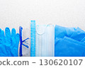Disposable medical face mask gloves hat glasses and scrubs laying on table flat lay view 130620107
