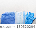 Healthcare background of disposable face mask, gloves, hat and scrubs laying on table flat lay view 130620204