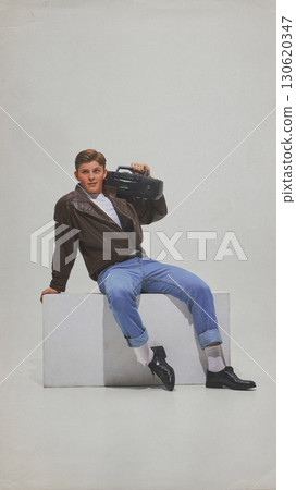 Man in casual retro outfit posing with boombox on shoulder smiling Man in casual retro outfit posing with boombox on shoulder smiling 130620347