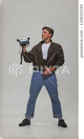Man in leather jacket holding vintage camcorder with confident pose Man in leather jacket holding vintage camcorder with confident pose 130620349