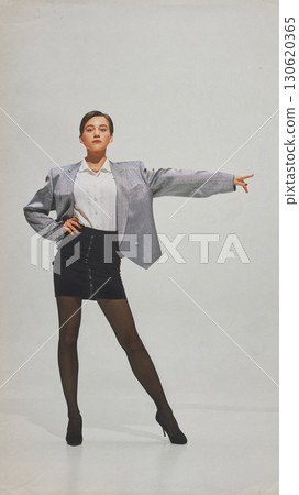 Strong woman in silver blazer pointing forward with powerful stance Strong woman in silver blazer pointing forward with powerful stance 130620365