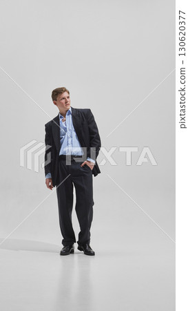 Young businessman posing confidently in black suit with relaxed charm Young businessman posing confidently in black suit with relaxed charm 130620377