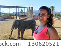 Smiling woman with elephant in background at Attica Zoo Athens, Greece. 130620521