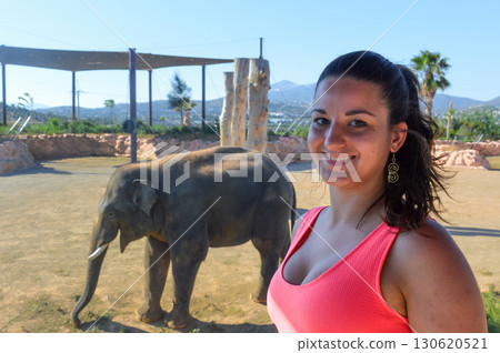 Smiling woman with elephant in background at Attica Zoo Athens, Greece. 130620521