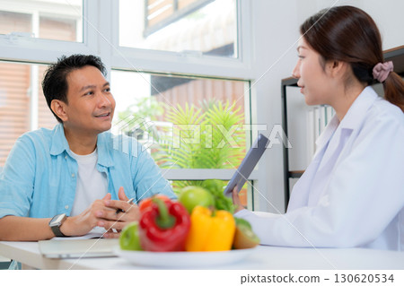 Asian nutritionist using tablet to explaining personalized meal plan with AI to patient. 130620534
