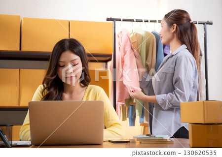 Two young asian businesswoman checking order clothes of customer for laptop computer. 130620535