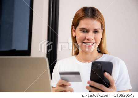 Happy young caucasian woman holding credit card or debit card paying with shopping online. Happy young caucasian woman holding credit card or debit card paying with shopping online. 130620545