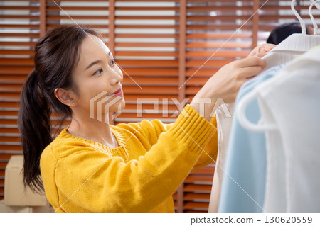 Two young asian woman arranging clothes in store for preparation delivery, seller choice clothes. 130620559