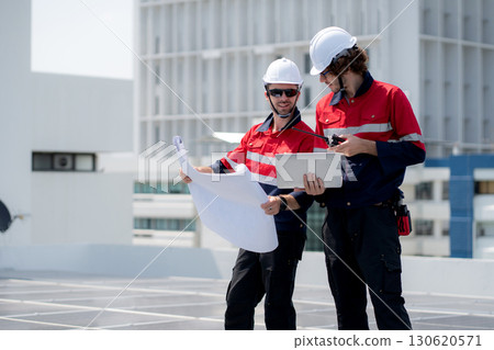 Two engineer checking solar energy system looking blueprint together. Two engineer checking solar energy system looking blueprint together. 130620571