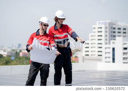 Two engineer checking solar energy system looking blueprint together. Two engineer checking solar energy system looking blueprint together. 130620572