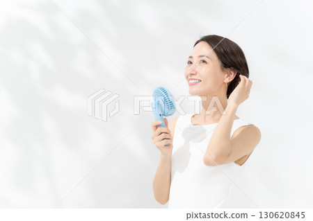 A woman who cools down with a handy fan A woman who cools down with a handy fan 130620845