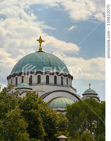 Saint Sava temple dome with golden crosses under clouds in Belgrade Serbia surrounded by trees. Religious architecture, Christian orthodoxy, cultural landmark, faith, tradition, history and spiritual Saint Sava temple dome with golden crosses under clouds in Belgrade Serbia surrounded by trees. Religious architecture, Christian orthodoxy, cultural landmark, faith, tradition, history and spiritual 130622070