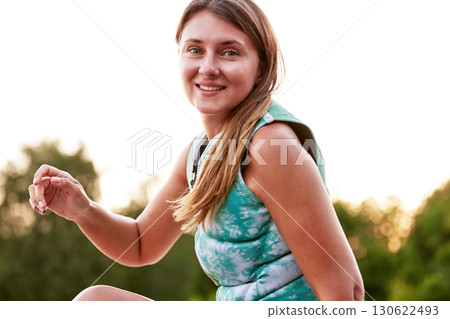 Smiling woman outdoors wearing activewear during a fitness session at sunset Smiling woman outdoors wearing activewear during a fitness session at sunset 130622493