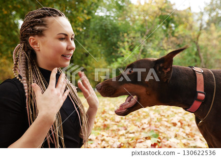 Woman interacting with a Doberman in a forest during autumn Woman interacting with a Doberman in a forest during autumn 130622536