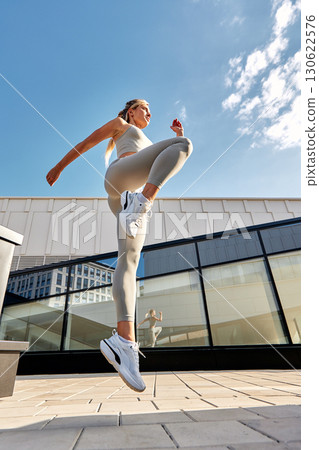 Athletic woman exercising outdoors against a modern building background Athletic woman exercising outdoors against a modern building background 130622576