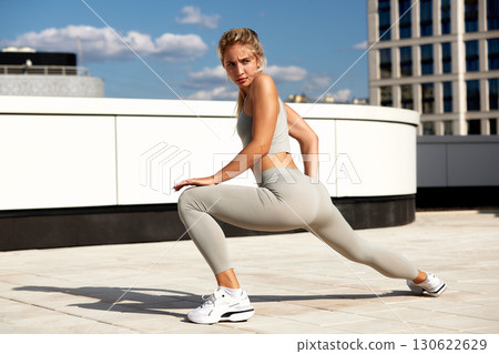 Woman stretching outdoors in activewear during a sunny day workout Woman stretching outdoors in activewear during a sunny day workout 130622629