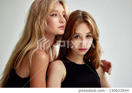 Two young women posing with close camaraderie and serene expressions 130622644