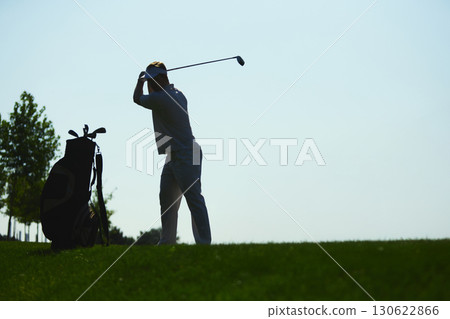 Golfer preparing swing silhouette with golf bag on green hill background 130622866