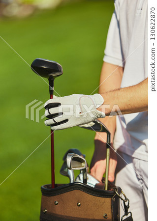 Golfer hand placing club back into golf bag on green field Golfer hand placing club back into golf bag on green field 130622870