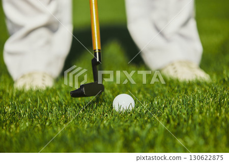 Close up golf putter preparing to hit ball on green grass field 130622875