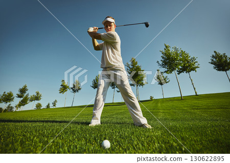Golfer holding backswing pose ready to strike golf ball 130622895