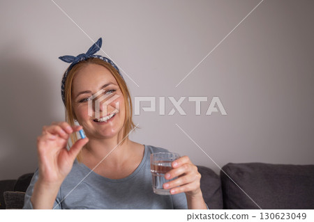 Smiling woman holding a blue pill with fingers .Health care, dietary supplements, treatment of depression and diseases Smiling woman holding a blue pill with fingers .Health care, dietary supplements, treatment of depression and diseases 130623049