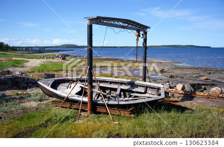 Weathered wooden boat on coastal landscape with blue sky by White Sea near Belomorsk in Karelia, nature of Russia 130623384