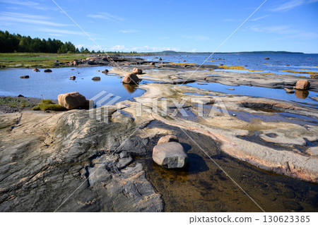 Tranquil landscape with rocky shore, water, clear blue sky and lush greenery by White Sea in Karelia, nature of Russia 130623385