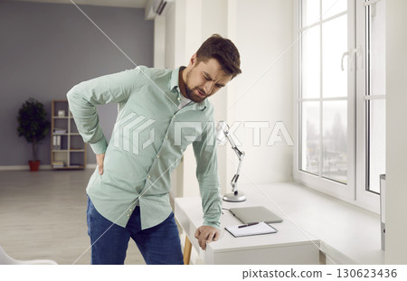 Tired, stressed young man is suffering from strong lumbago pain in his lower back 130623436