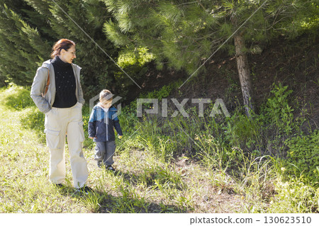 Mother and son walking through sunny forest trail Mother and son walking through sunny forest trail 130623510