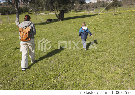 Mother and son walking in green meadow on sunny day Mother and son walking in green meadow on sunny day 130623552