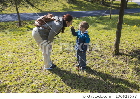 Mother and son smelling a flower in the park during springtime Mother and son smelling a flower in the park during springtime 130623558