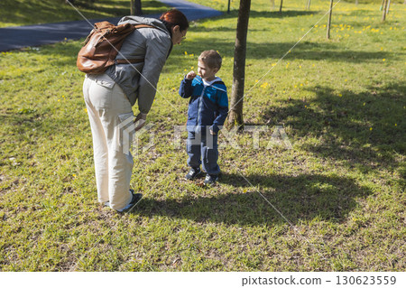 Grandmother and grandson exploring nature in park on sunny day 130623559