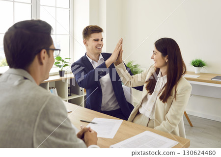 Happy couple meet with real estate agent, sign contract and high five each other Happy couple meet with real estate agent, sign contract and high five each other 130624480