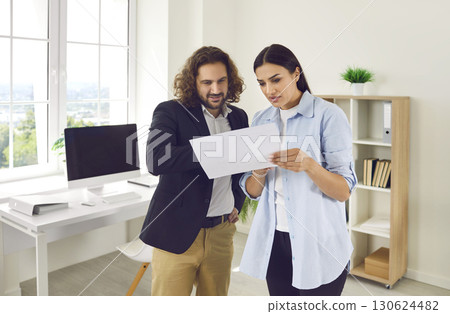 Two business people or corporate employees working together and discussing some documents Two business people or corporate employees working together and discussing some documents 130624482