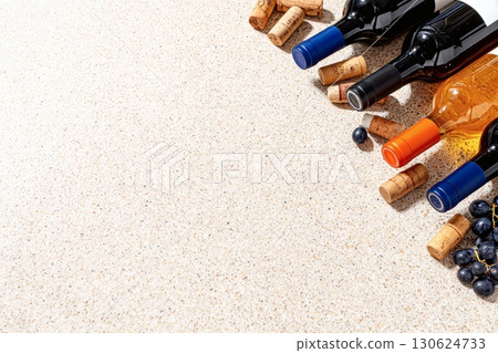 Wine bottles on textured sandy floor, grape and cork mockups, top-down flat lay view, empty space for text overlay, photorealistic composition ideal for wine advertising or social media 130624733