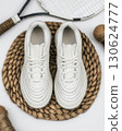 White sneakers with thick sole placed on woven rug beside tennis racket and sports gear. High resolution flat lay product mockup for fashion advertising or athletic lifestyle promotion 130624777