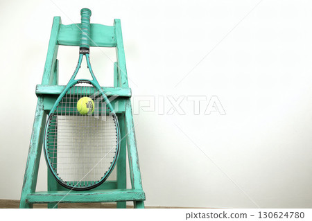 Studio shot of tennis racket leaning on chair with ball on clean white background. Minimal sport concept ideal for product mockup advertising poster or healthy lifestyle promotion design 130624780