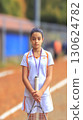 Junior tennis player holding racket in both hands with blurred playground background. Sport concept with copy space above ideal for training fitness competition or motivational poster 130624782