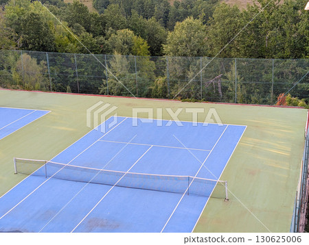 Blue and green tennis court with white lines and net. Sports tourism in mountain village. Blue and green tennis court with white lines and net. Sports tourism in mountain village. 130625006