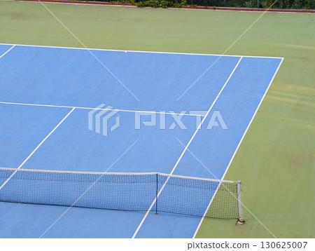 Blue and green tennis court with white lines and net. Sports tourism in mountain village. 130625007