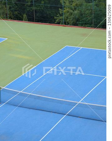 Blue and green tennis court with white lines and net. Sports tourism in mountain village. 130625009