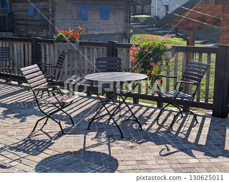 Round table with black chairs on stone square near traditional buildings. Outdoor cafe in Drvengrad. 130625011
