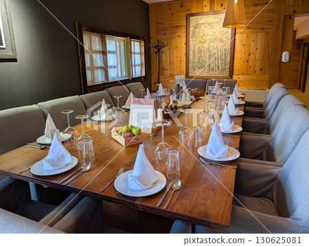 Reserved rustic dining table with portrait on wall. Heritage, tradition, hospitality and cultural dining environment. Reserved rustic dining table with portrait on wall. Heritage, tradition, hospitality and cultural dining environment. 130625081